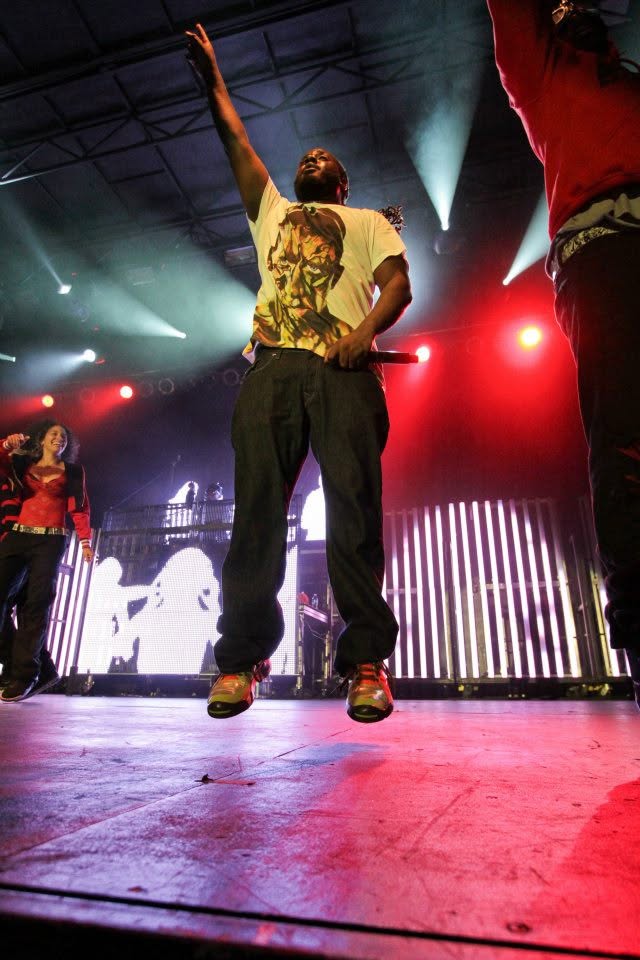T-Pain jumping mid-performance with arm raised under red lights