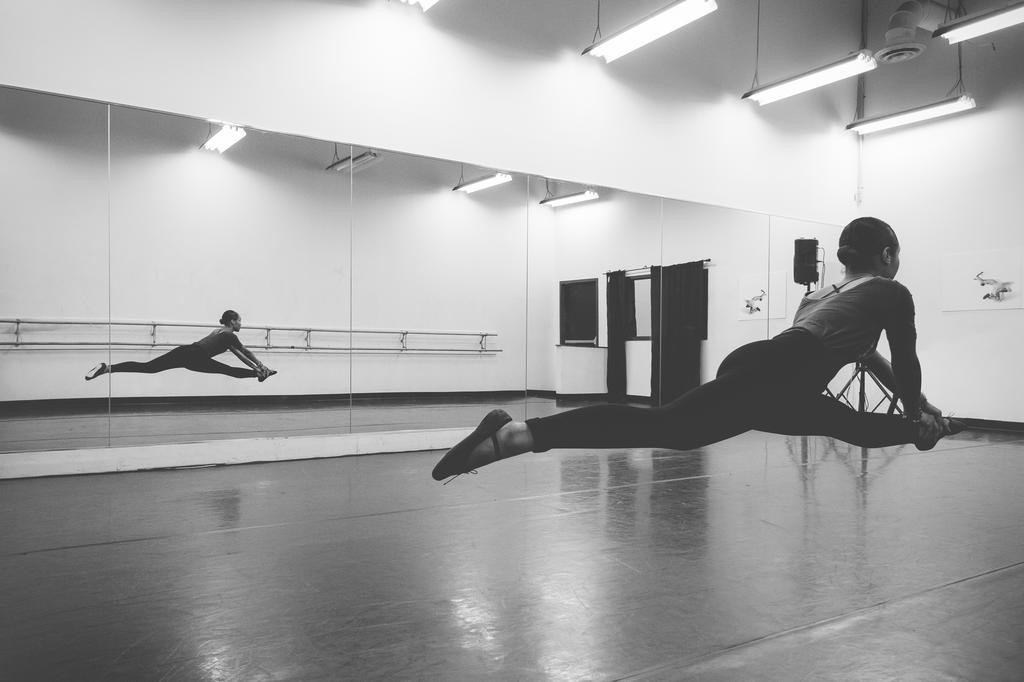 Dancer mid-leap in a mirrored studio