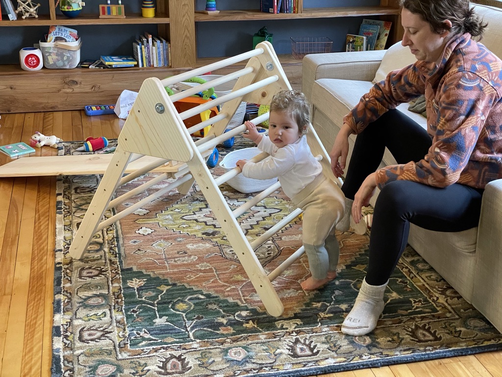 Child climbing a handmade wooden Pikler triangle