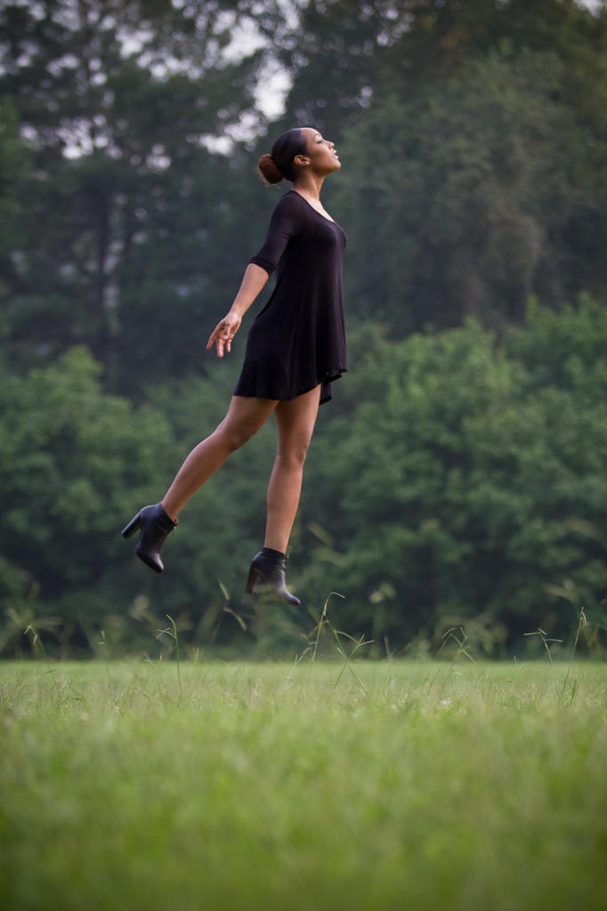 Figure in a black dress suspended above a misty field