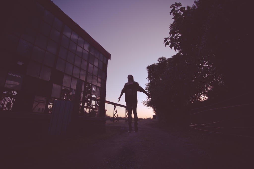 Silhouetted figure suspended at dusk beside an old building