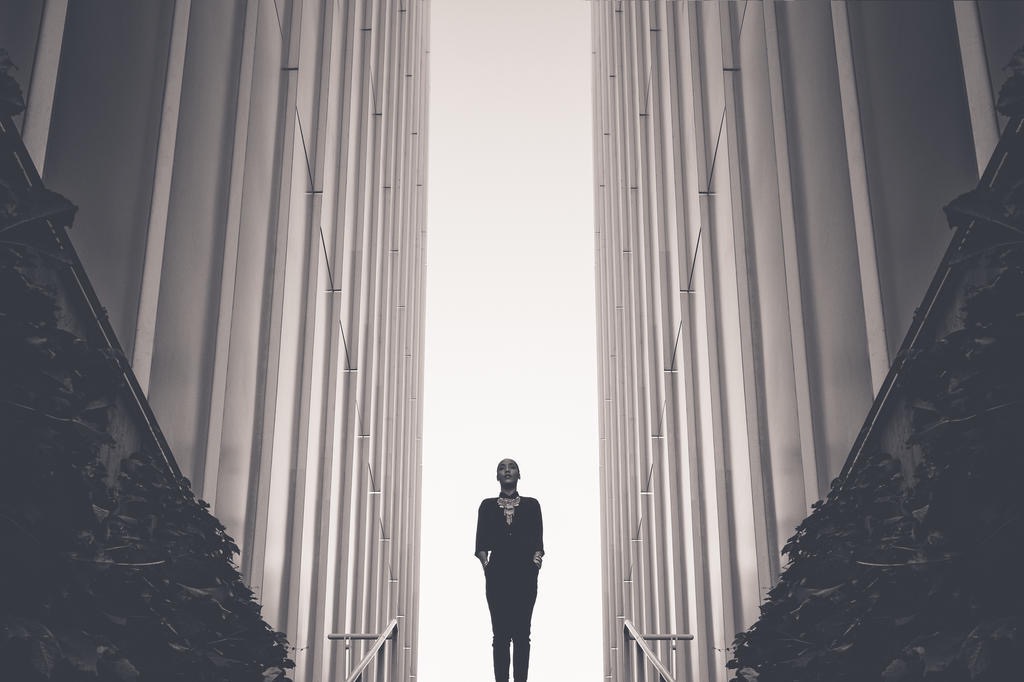 Figure standing between towering columns in monochrome