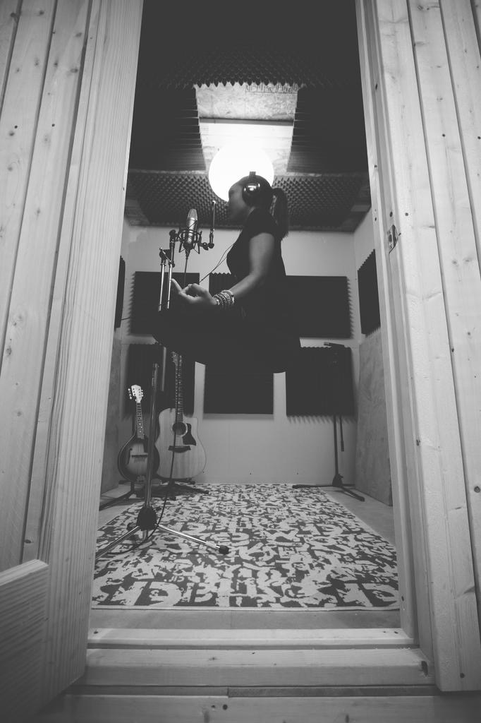 Vocalist recording in a wood-paneled studio booth