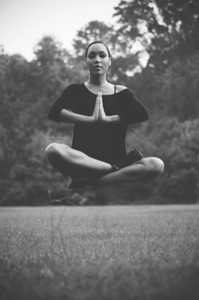 Figure seated in a meditative pose, levitating over a meadow