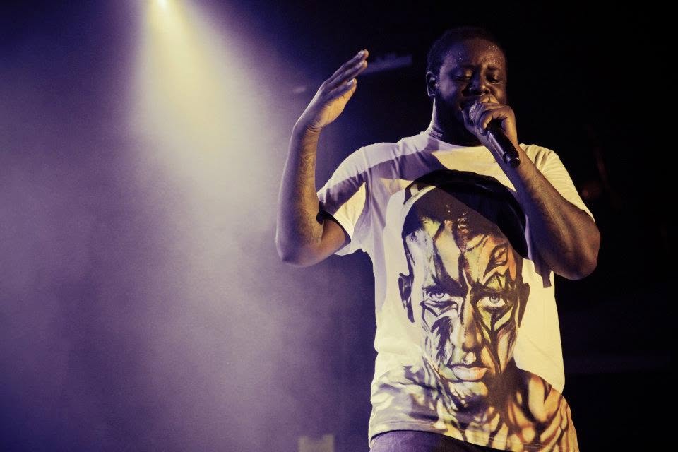 T-Pain performing with microphone, hand raised